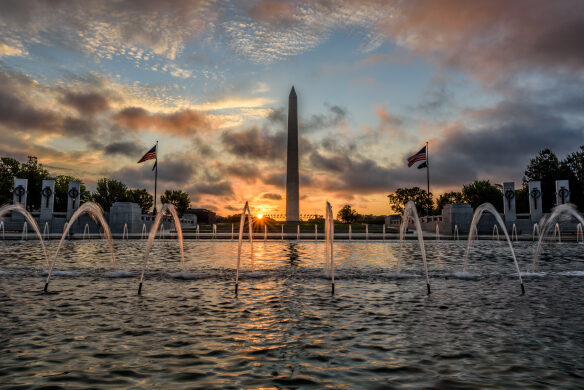 The rising sun burns the sky behind the Washington Monument